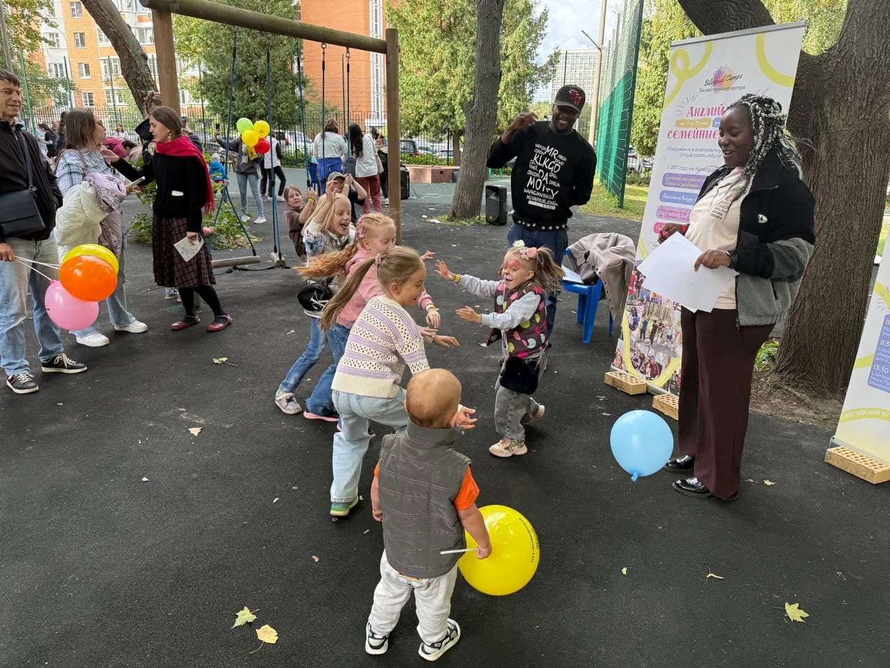 Children playing with balloons while adults cheer them on