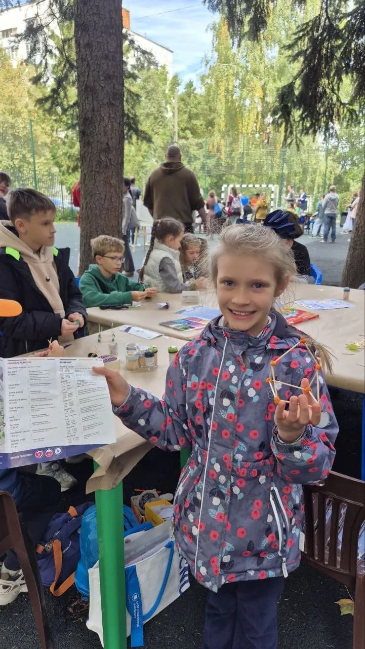 A girl showing a bead-and-stick model she made at a workshop