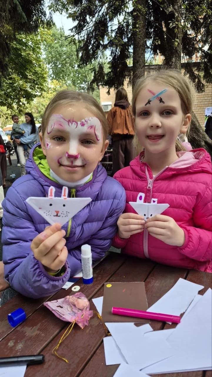 Two girls with face paint holding paper cards