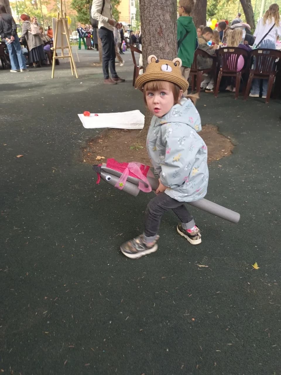 A child in a bear hat holding a handmade hobby horse