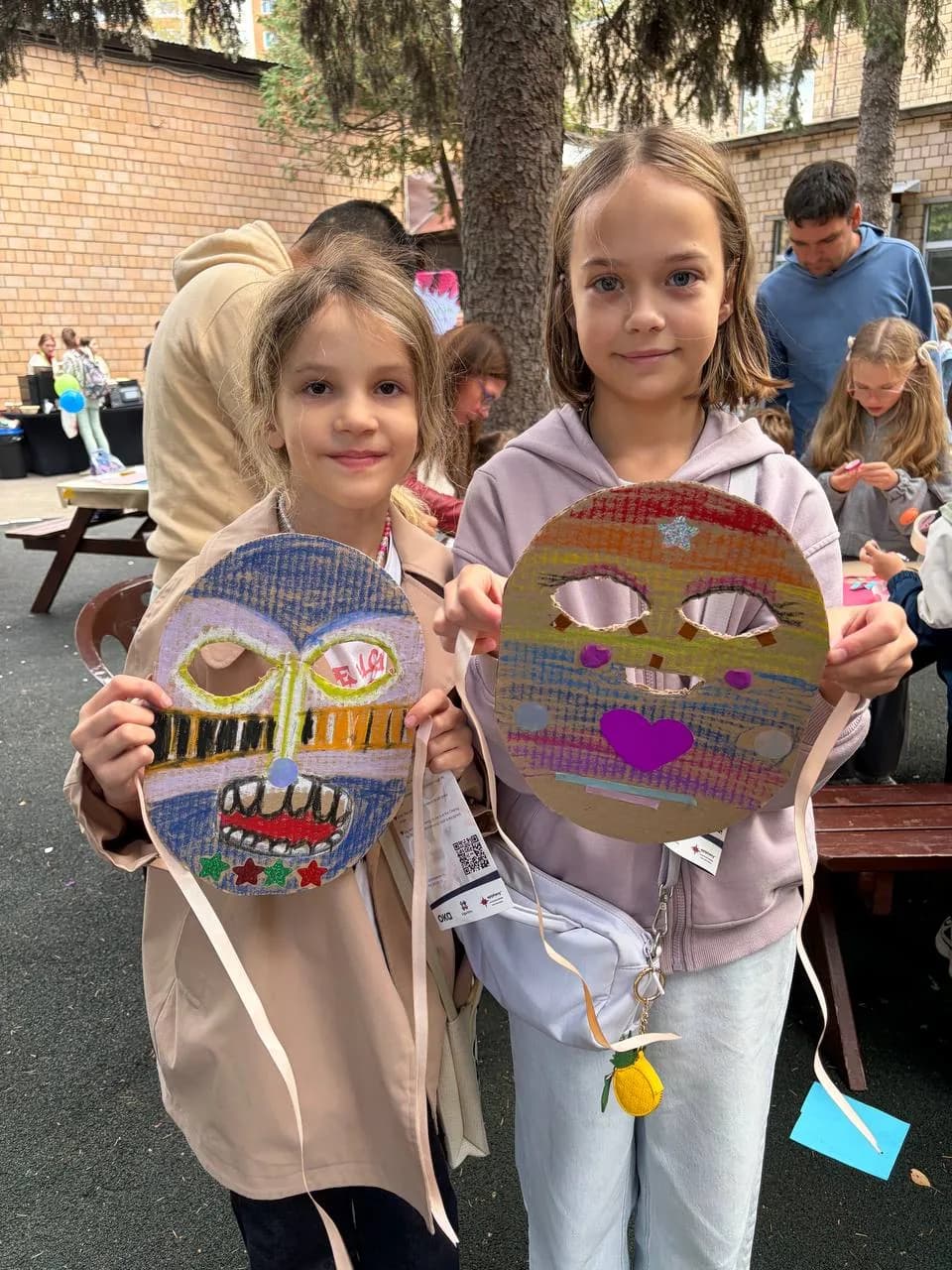 Two girls holding colourful handmade masks