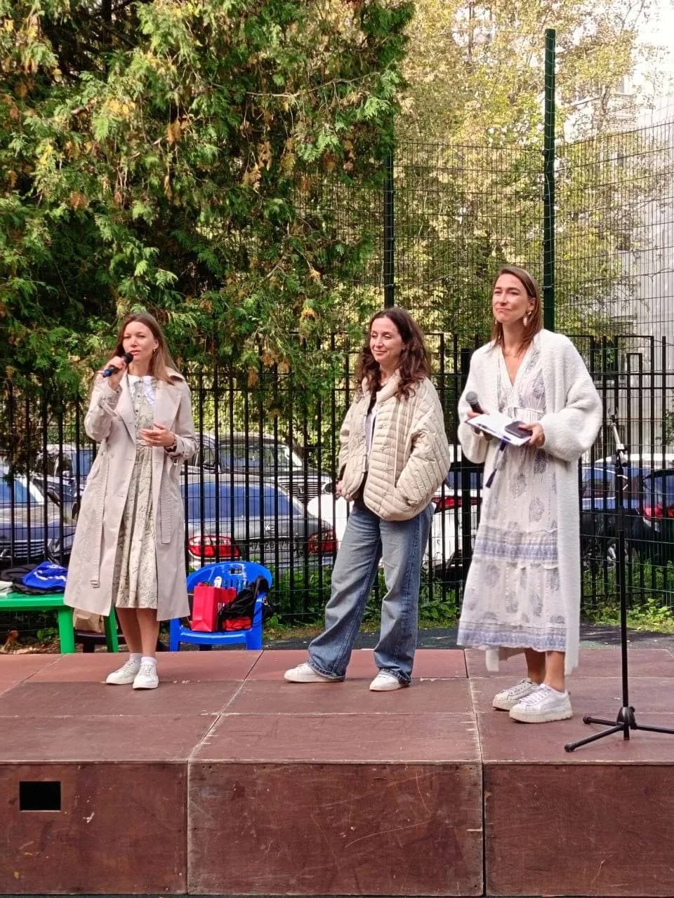 Three women speaking on the wooden stage