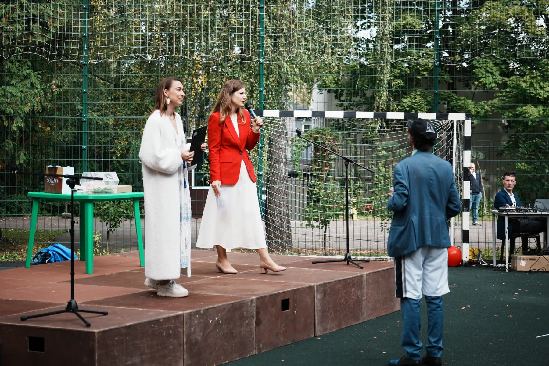 Two speakers on the outdoor stage, one holding a microphone