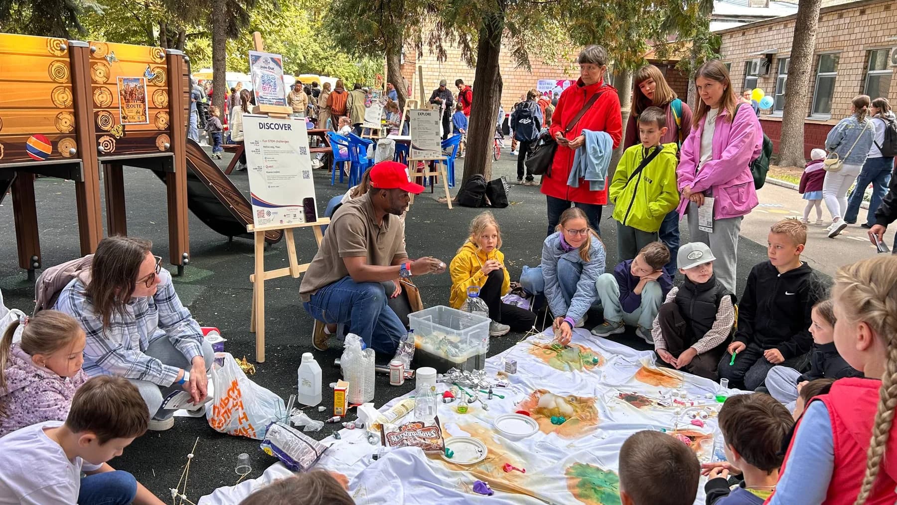 Children and parents sitting on the ground around a hands-on workshop