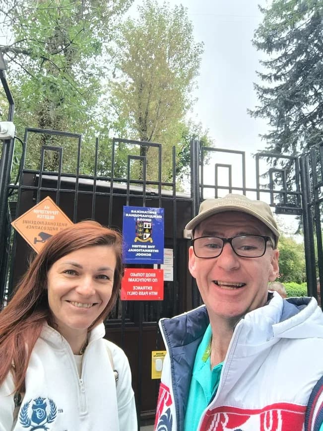 Olga Ikonnikova and Hugh Mc Enaney at the gate of the British International School